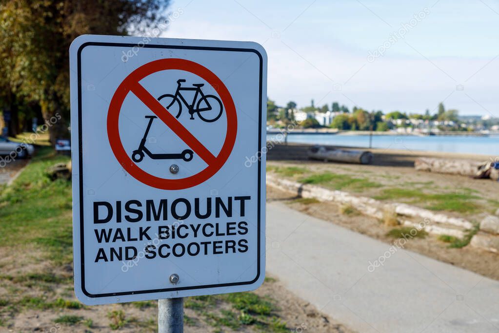 Sign instructing to dismount and walk bicycles and scooters in a Vancouver park