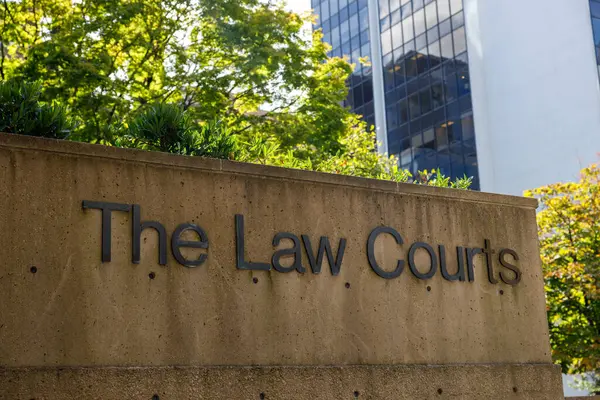 Modern hukuk mahkemeleri beton duvarlı giriş tabelası yapıyorlar, yemyeşil bitki örtüsüyle çevrili.