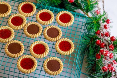 Bir tel askıda reçelli ve fındıklı Noel kurabiyeleri soğuyor.