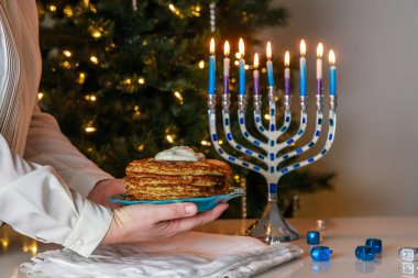 Menorah and potato latkes on a Jewish holiday table during Hanukkah. clipart