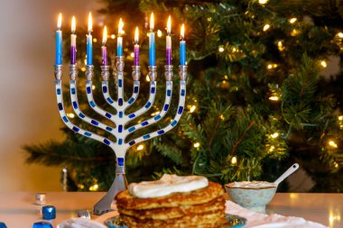 Yahudi bayramında menorah ve çıtır patatesli latkelerle yemek..