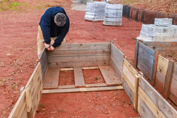A raised garden bed is being built by men using a wooden frame.