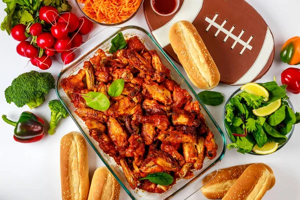 A football game party includes wings, dip sauce and salad.