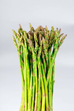 Canlı taze kuşkonmaz paketi, tarafsız arka plana karşı dimdik duruyor. Yeşil saplar ve hassas ipuçları sergiliyor. Mutfak yemekleri veya sağlığa duyarlı yemekler için mükemmel..