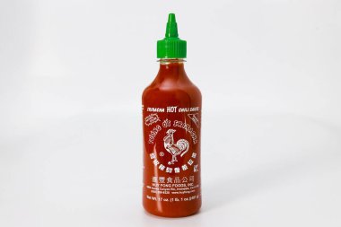 4 Şubat 2023. Spartanburg, SC USA. Bir şişe Sriracha acı biber sosu sade beyaz arka plana karşı dimdik ayakta duruyor. İçindeki canlı kırmızı sos yeşil kapakla çelişiyor..