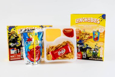 July 6, 2023. Spartanburg, SC USA. Lunchables kit featuring cheese dip, crunchy chips, and sweet treat alongside fruit drink. clipart