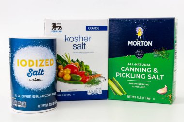 March 6, 2023. Spartanburg, SC USA. Three types of salt arranged neatly on clean surface. Packaging includes labels for iodized salt, kosher salt, and canning salt. clipart