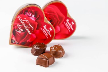 July 6, 2023. Spartanburg, SC USA. Heart-shaped boxes filled with assorted chocolates are displayed alongside three individual chocolates. The setting suggests a Valentines Day theme. clipart