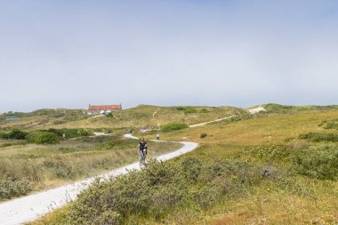 Terschelling, The Netherlands - June 10, 2023: Cycling road through the dunes from Formerum to the beach at Wadden island Terschelling in Friesland province in The Netherlands clipart