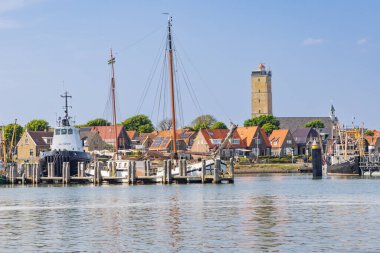 Terschelling, Hollanda - 11 Haziran 2023: Hollanda 'nın Friesland ilindeki Wadden Adası Terschelling' de römorkör Hunter ve Brandaris deniz feneriyle Batı Terschelling kenti