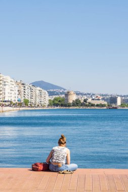Yunanistan 'ın orta Makedonya bölgesindeki Selanik' in merkezinde yer alan beyaz kule manzaralı Ege Koyu boyunca dinlenen insanlar