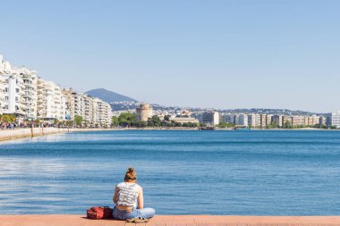 Yunanistan 'ın orta Makedonya bölgesindeki Selanik' in merkezinde yer alan beyaz kule manzaralı Ege Koyu boyunca dinlenen insanlar