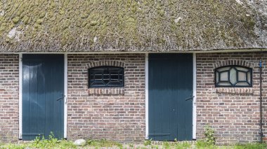 Hollanda, Drenthe 'de Orvelte' de ahşap kapılı ve çiftlik pencereli tuğla duvar..