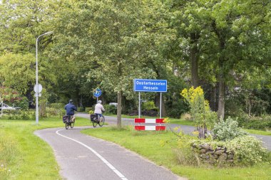 Oosterhesselen, Hollanda - 11 Temmuz 2024: Hollanda 'nın Drenthe kentindeki Oosterhesselen Hesseln Belediyesi Coevorden plasenta tabelalarını geçen son sınıf bisikletçisi.