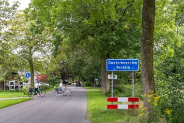 Oosterhesselen, Hollanda - 11 Temmuz 2024: Hollanda 'nın Drenthe kentindeki Oosterhesselen Hesseln Belediyesi Coevorden plasenta tabelalarını geçen son sınıf bisikletçisi.
