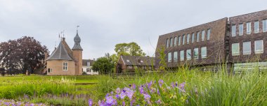 Panorama view of beautiful park and garden with purple and blue flowers near the city hall and castle of Coevorden in Drenthe The Netherlands clipart