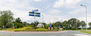 Oostwerhesselen, The Netherlands - July 11, 2024: Beautiful green designed roundabout with the old church of Oosterhesselen Municipality Coevorden in Drenthe in The Netherlands. clipart