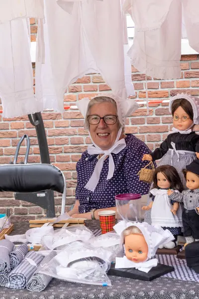 stock image Barneveld, The Netherlands - August 1, 2024: Woman in farmers clothes demonstrating the sewing of white linen at Traditional Veluwe market in Barneveld Gelderland province in The Netherlands