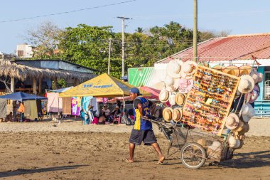 San Juan del Sur, Nikaragua - 23 Mart 2024: Satıcılar güneybatı Nikaragua 'daki Rivas bölgesinde Pasifik Okyanusu kıyısındaki San Juan del Sur sahil kasabasında mal satmak için sahilde yürüyorlar.