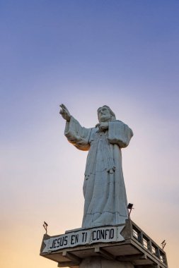 San Juan del Sur, Nicaragua - March 23, 2024: Towering contemporary Christ of the Mercy statue standing on a cliff above the bay of San Juan del Sur. clipart