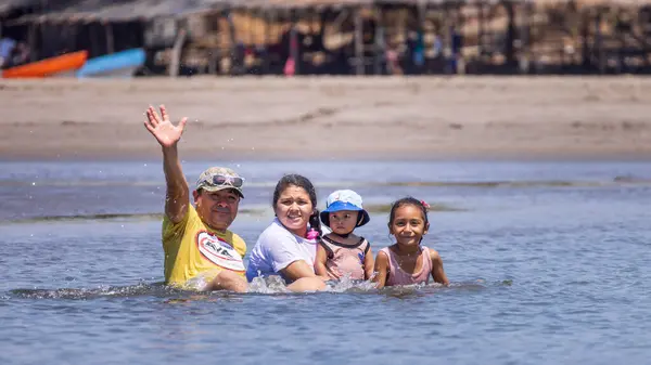 stock image Las Penitas, Nicaragua - March 17, 2024: Man with family in the water waving at the camera in Las Penitas entrance to Juan Venado island nature reserve in Nicaragua Central America