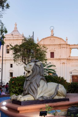Leon, Nikaragua - 17 Mart 2024: Aslan heykeli ve çeşmesi Nikaragua 'da günbatımında Leon' un beyaz koloni katedralinin önünde