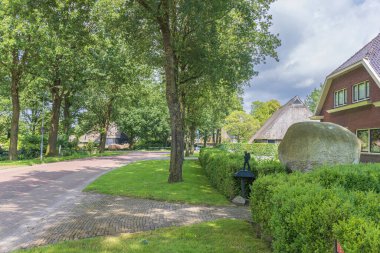 Gees, Hollanda - 22 Haziran 2024: Hollanda Drenthe 'deki Gees adlı küçük köyün göbeğindeki Drenthepad yolu boyunca büyük kaya ve yürüyüş işareti