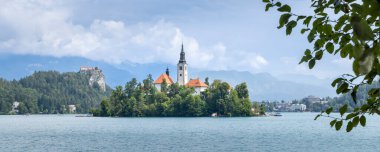 Slovenya 'nın Gorenjska bölgesindeki Bled şehrinin beyaz kilise ve Bled kalesi yüksek kayalıklarda bulunan görkemli Bled Adası manzarası