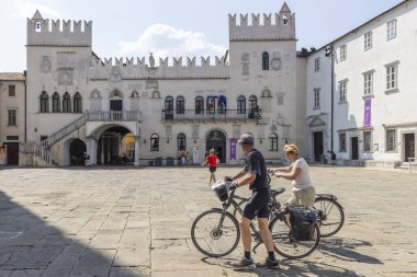 Koper, Slovenya - 30 Ağustos 2024: Slovenya 'daki Adriyatik denizi boyunca uzanan Istrian yarımadasındaki Tito Meydanı' ndaki Praetorian Sarayı 'ndan geçen turist