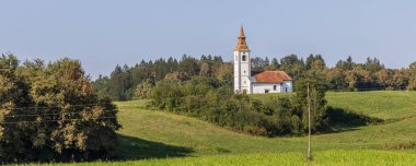Slovenya 'nın Trebnje kentindeki tipik Sloven köyü Velika Loka yaz mevsiminde Slovenya' da tepede kırmızı çatılı beyaz bir kilise