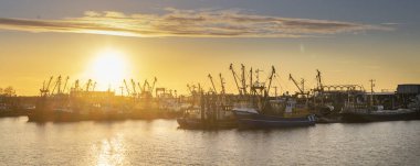 Hollanda limanı Lauwersoog 'un gün batımı manzarası Hollanda' nın Groningen kentindeki Waddensea boyunca uzanan balıkçı gemileriyle