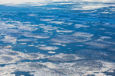 Ice floes on a blue lake water in sunny cold winter day. An abstract background texture photo