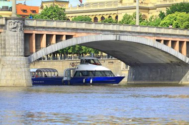 Bir zevk gemisi, güneşli bir günde köprünün altından geçerek antik mimarinin arka planına karşı çıkar.