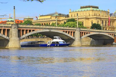 Bir zevk gemisi, güneşli bir günde köprünün altından geçerek antik mimarinin arka planına karşı çıkar.