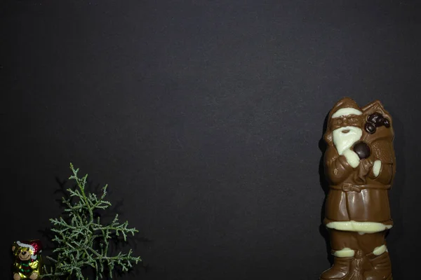 New Year\'s decorations chocolate bear with Santa Claus made of dark and white chocolate and a Christmas tree on a black background
