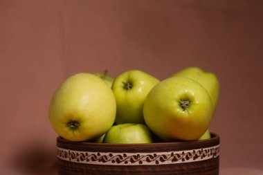 Çamurdan bir tabakta arkaplandaki lezzetli, sulu, altın elmalar. Arkaplanda pembe bir süs var.