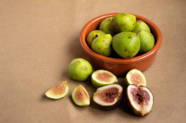 Taze incirli kil kasesi ve açık kahverengi arka planda incir parçaları.