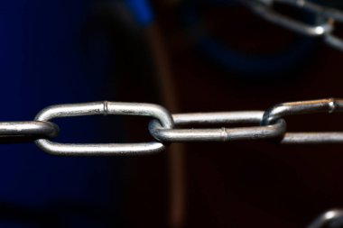 Kaynaklı dikişli, koyu arkaplanı bulanık çelik bir zincirin yakın çekimi.