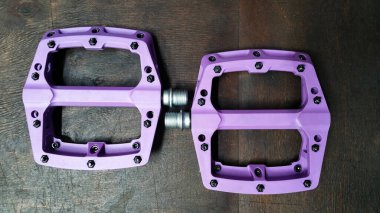 İki mavi plastik düz pedal, arka planda koyu tahta bir arka plan görünümünde değiştirilebilir çiviler.