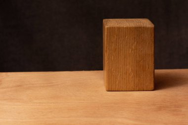 Karanlık arka planda Paralelepied ahşap bir figürün yakın plan fotoğrafı. Ahşap bir masada hayat.