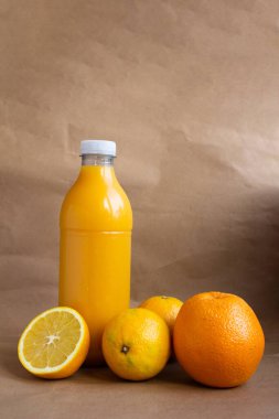 natürmort. İçinde portakal suyu olan plastik bir şişe, üç olgun meyve ve portakalın yarısını kesmiş. Yakın plan.