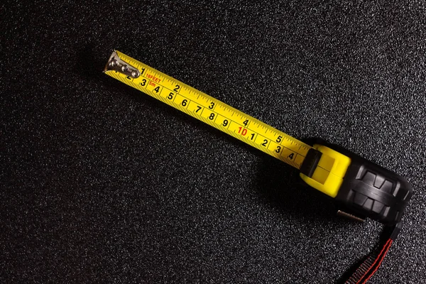 opened tape measure on a black speckled background top view