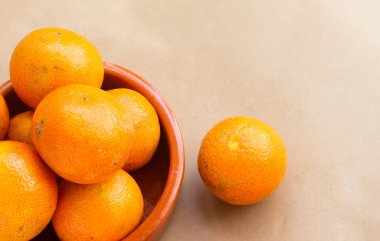 Yakın plan - açık kahverengi arkaplanda bir kase mandalina manzarası