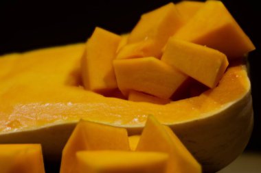 Balkabağının içindeki balkabağı parçalarının siyah arka planda yakın plan görüntüsü.