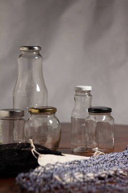 Yeniden kullanılabilen konteynırlar - tekrar kullanım için bez torbaları ve cam şişeler - koyu tahta bir masa üzerinde açık arkaplanlı