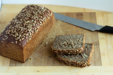bread in the shape of a brick with cut pieces and a knife - on a wooden cutting board