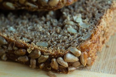 close-up of a cut slice of wholesome bread with sunflower seeds with defocused background