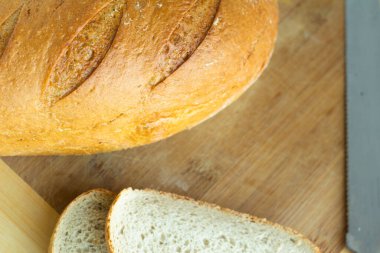 ruddy wheat bread with slanting cuts and cut pieces of bread - on a light wooden background