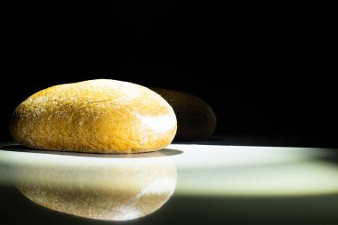 light wheat bread on the table with bread reflection - on black background