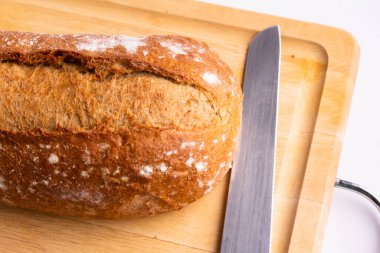 close-up bread with a longitudinal cut on a wooden cutting board and with a knife top view